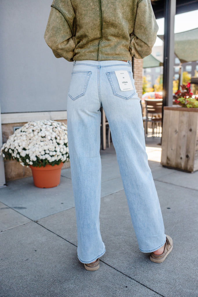 Person wearing light blue jeans with a visible brand tag, standing outdoors.