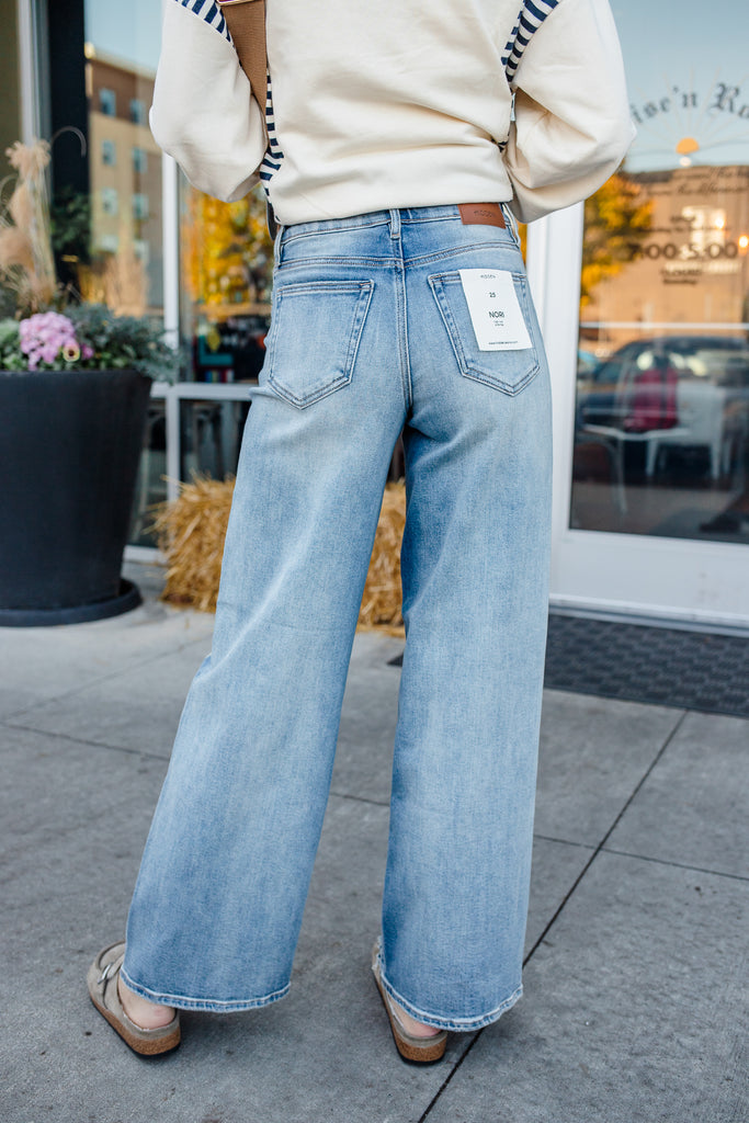 Person wearing light blue jeans with a blurred background