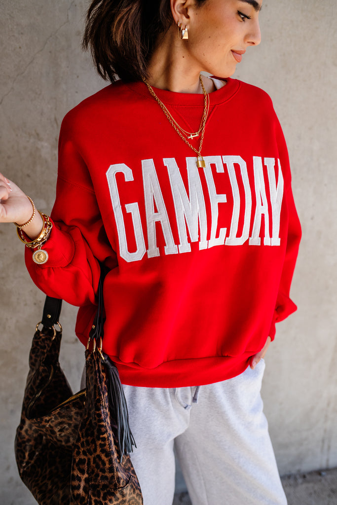 Person wearing a red 'GAMEDAY' sweatshirt with a leopard print bag.