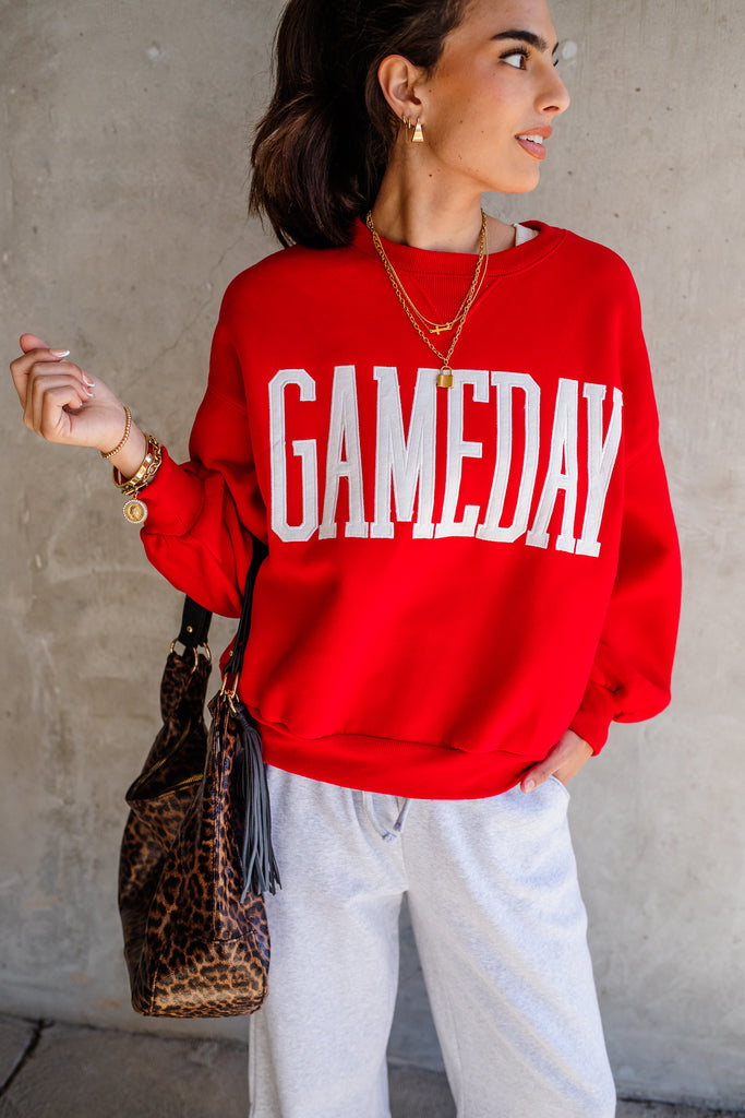 Person wearing a red 'GAMEDAY' sweatshirt with a leopard print bag.
