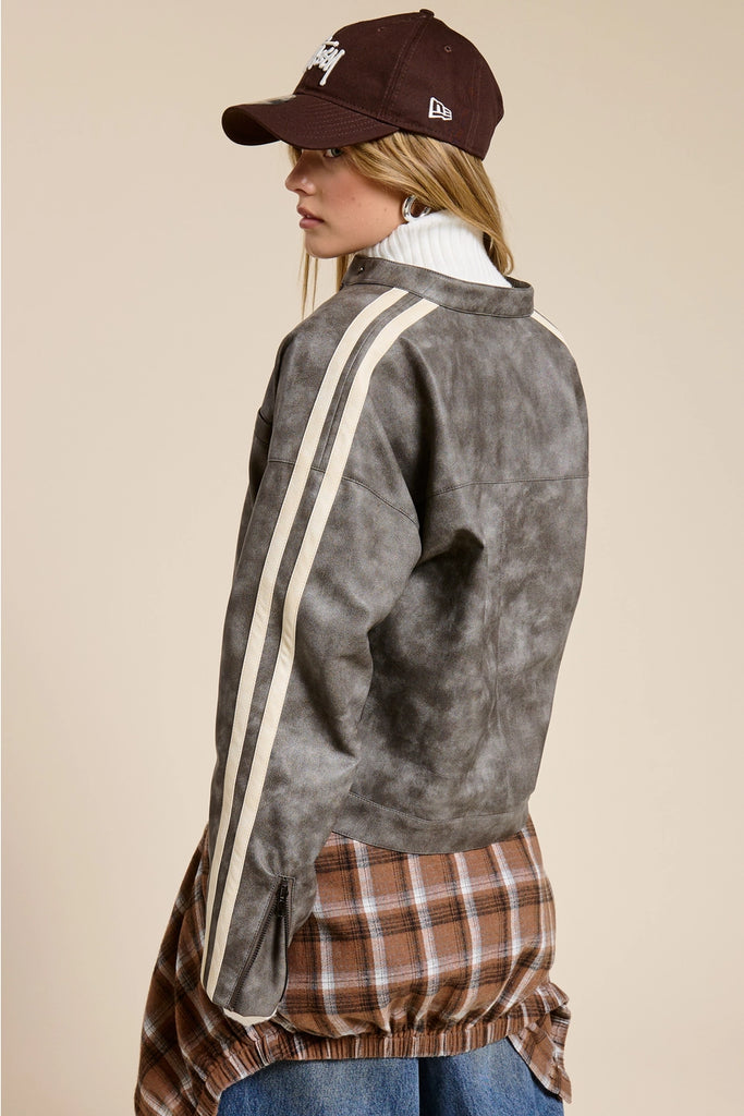 Person wearing a gray jacket with white stripes, plaid shirt, and brown cap on a beige background