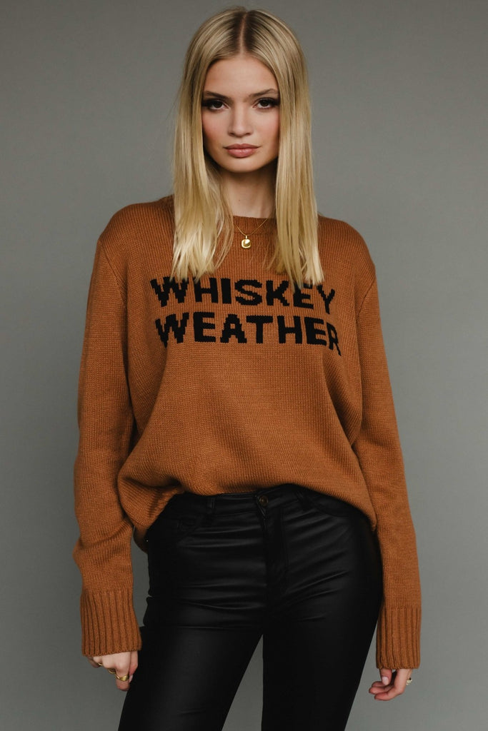 Woman wearing a brown sweater with 'WHISKEY WEATHER' text on a gray background