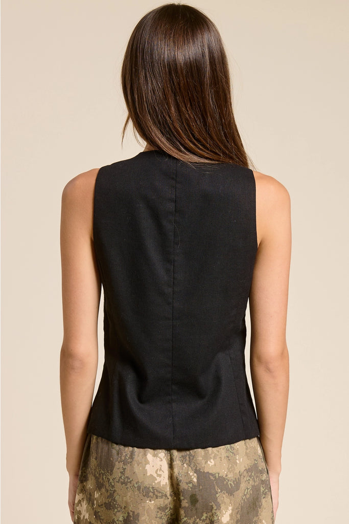 Woman wearing a black sleeveless top with a beige background