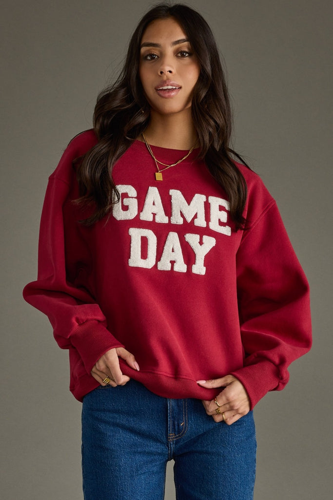 Woman wearing a red 'GAME DAY' sweatshirt against a gray background